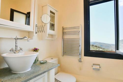 uma casa de banho com um lavatório, um WC e uma janela. em Villa Esmeralda Kea em Fotimárion