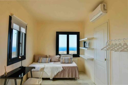 ein Schlafzimmer mit einem Bett und zwei Fenstern in der Unterkunft Villa Esmeralda Kea in Fotimárion