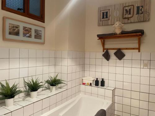 uma casa de banho com uma banheira com vasos de plantas em Gîte de Solama avec SPA em Balléville
