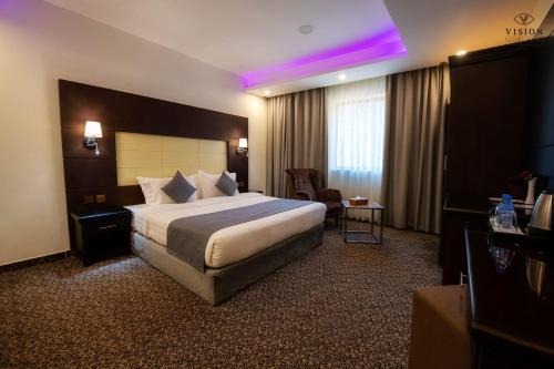 une chambre d'hôtel avec un lit et une lumière violette dans l'établissement فندق الرؤية محافظة الداير بني مالك, à Al Buhrah