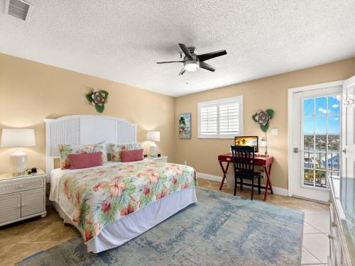 Schlafzimmer mit einem Bett, einem Schreibtisch und einem Deckenventilator in der Unterkunft Sea Breeze 708 in St Pete Beach