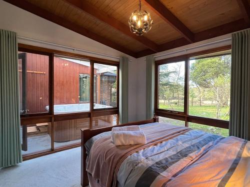 a bedroom with a bed and large windows at Wandjoo Cottage Cranbourne in Lyndhurst South