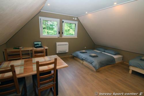 1 dormitorio con cama, mesa, cama y escritorio en Base camp - Apartments & Rooms, en Bovec