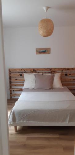 a bedroom with a white bed with a wooden headboard at La Petite Perle in Andernos-les-Bains