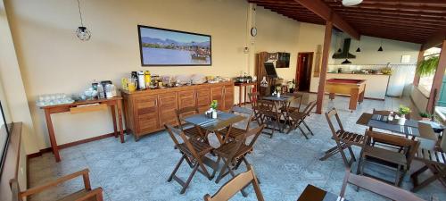 ein Restaurant mit Holztischen und -stühlen und einer Theke in der Unterkunft Pousada das Saíras in Paraty