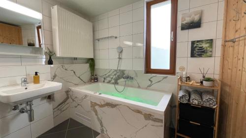 a bathroom with a bath tub and a sink at Wunderschöne Wohnung am See mit Sauna & Whirlpool in Unterterzen