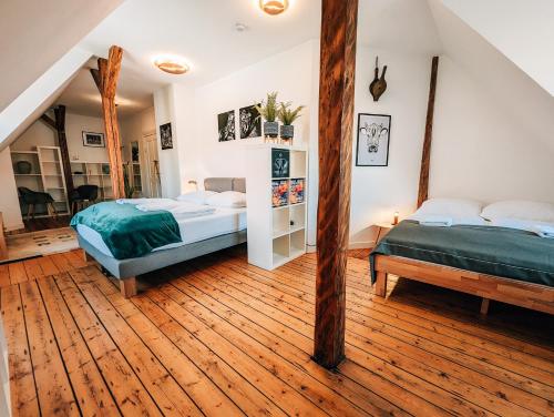 2 camas en una habitación con suelo de madera en 4-Schlafzimmer-Terrassensuite Oasis - WORKSPACE EM-APARTMENTS DEUTSCHLAND, en Bielefeld