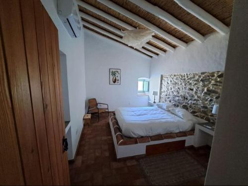 1 dormitorio con 1 cama grande y pared de piedra en Casa na horta, planície alentejana 