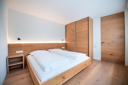 - une chambre avec un grand lit blanc et des murs en bois dans l'établissement Villa Mayr, à Ortisei