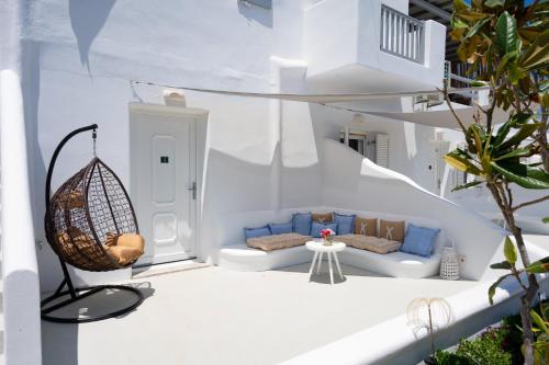 een witte kamer met een bank en een schommel bij Vaqueros in Mykonos-stad