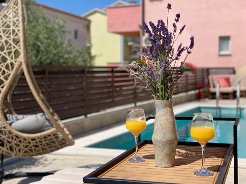 two glasses of orange juice and a vase with flowers at Charming Villa Ira with Pool in Krk