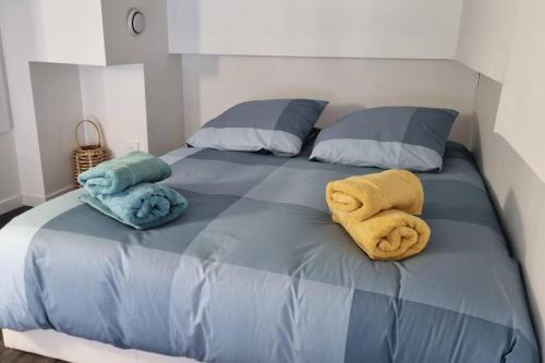 a bed with two towels and two pillows on it at CASITA aux portes de paris in Bagneux
