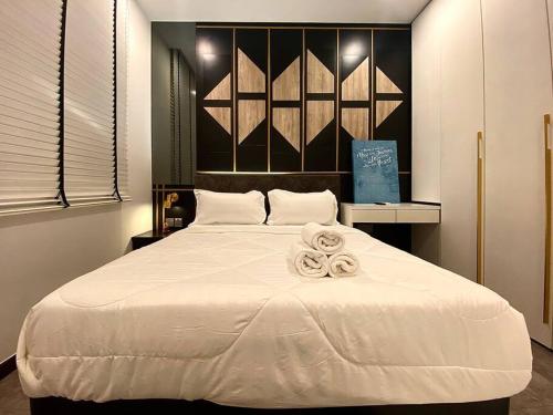 una camera da letto con un grande letto bianco con asciugamani di SIX Boutique Residence @ Ipoh Garden Landed House 8pax a Ipoh
