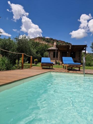 a swimming pool with two benches and a house at Sant'Anselmo in Bagnoregio