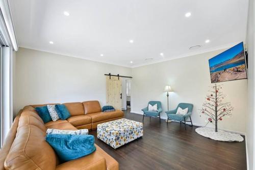 a living room with a brown couch and two chairs at Nuach cottage - Beautiful Family home in Leura in Leura