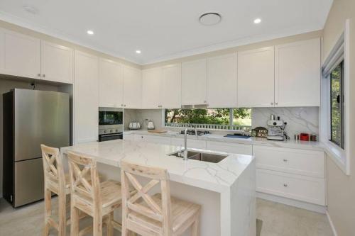 a kitchen with white cabinets and a kitchen island with chairs at Nuach cottage - Beautiful Family home in Leura in Leura