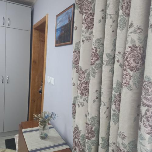 a room with a curtain and a table with a vase at Три горішки in Yaremche