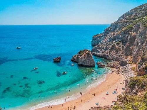 a beach with a bunch of people in the water at Casa da Piscina in Sesimbra