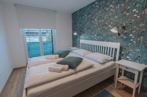 1 dormitorio con 2 camas y pared con papel pintado con motivos florales en APARTMA LAMBERGER, en Žirovnica