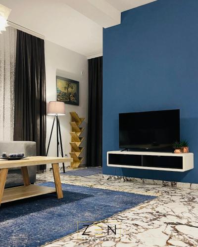 a living room with a large television on a blue wall at Zen Apartments Pejë in Peje