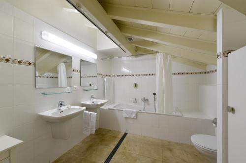 a bathroom with two sinks and a tub and a toilet at L'Hôtel by Hostellerie du Château in Rolle