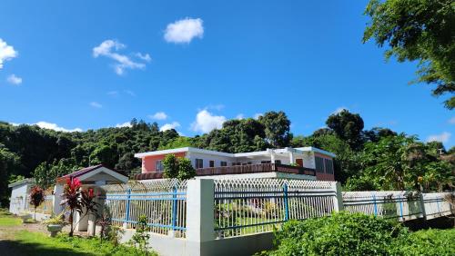 a house with a white fence and trees at Ocean Heart Hotel in Sigatoka