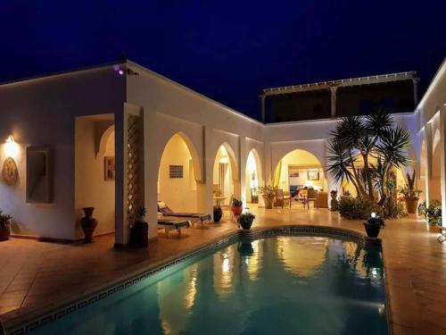 a house with a swimming pool at night at Chambre d'hôtes, Dar l'air du temps in Aghīr