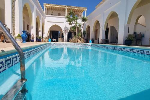 a swimming pool with blue water in a building at Chambre d'hôtes, Dar l'air du temps in Aghīr