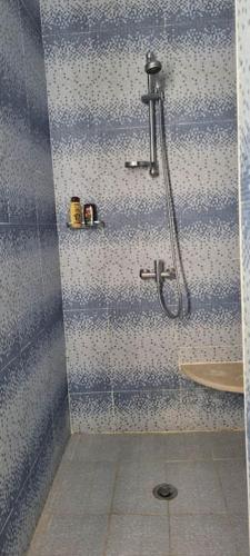 a shower in a bathroom with blue and white tiles at Chambre d'hôtes, Dar l'air du temps in Aghīr