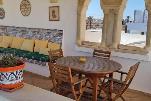 a table and chairs in a living room with a couch at Chambre d'hôtes, Dar l'air du temps in Aghīr