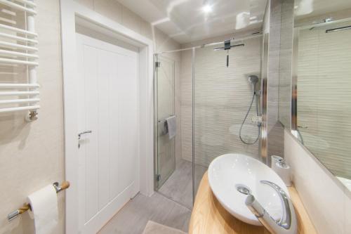 a white bathroom with a sink and a shower at Apartment Kaisermöwe in Świnoujście