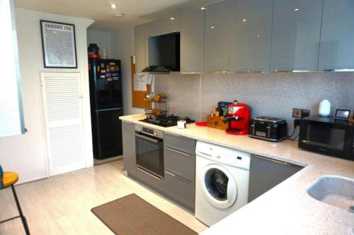 a kitchen with a stove and a washing machine at Lovely family home in Rainham, Kent in Rainham