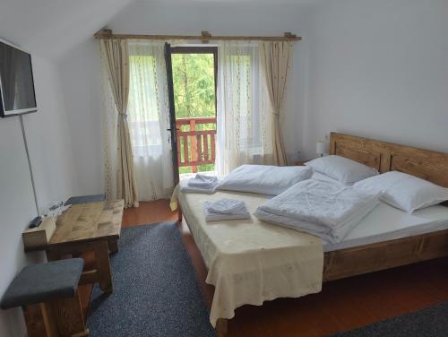 um quarto com 2 camas, uma mesa e uma janela em Pensiunea Trei Brazi Arieseni em Arieşeni