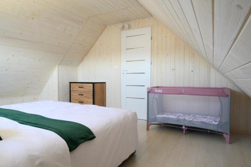 a bedroom with a bed and a crib in a attic at Resort Za Lasem in Jarosławiec
