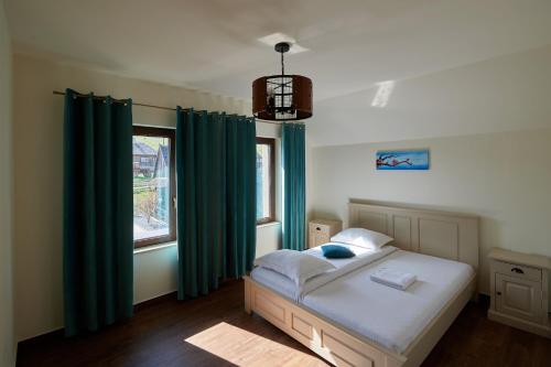 a bedroom with a bed with green curtains and a window at Grand Lake House in Giurcuţa de Sus