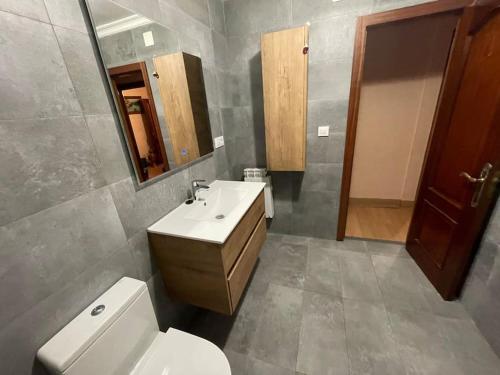 ein Badezimmer mit einem Waschbecken, einem WC und einem Spiegel in der Unterkunft Piso acogedor in Soto del Barco