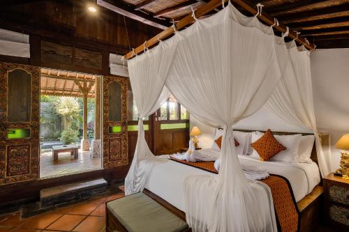 een slaapkamer met een hemelbed bij Roshan Ubud Villa in Ubud