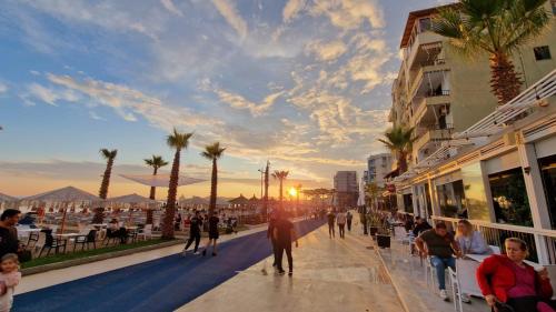 mensen lopen over een stoep naast een strand met palmbomen bij Donel Apartment in Durrës