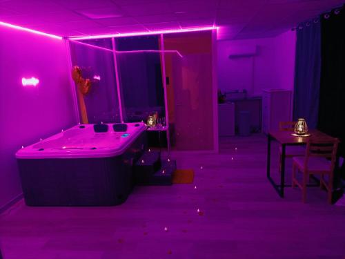 Cette chambre violette comprend une baignoire et une table. dans l'établissement CocoonSPA LoveRoom Jacuzzi, à Toulouse