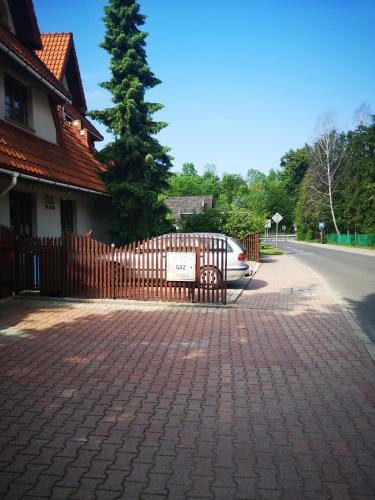 a fence with a car parked next to a house at zielony zakątek in Nowy Targ