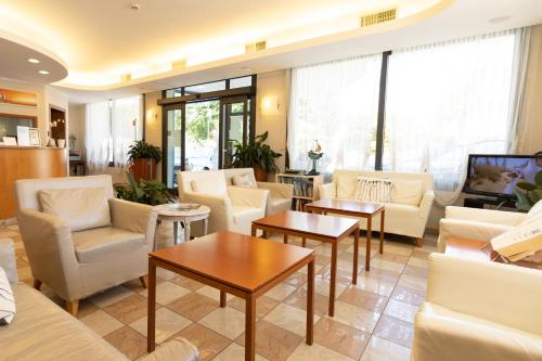 a living room with white couches and tables at Hotel Crystal in Caorle