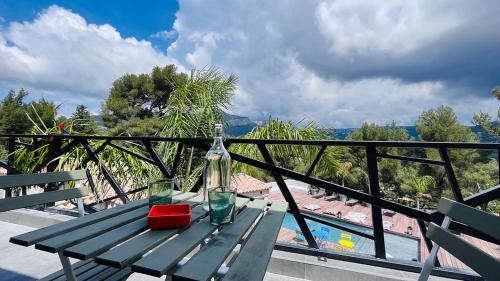 a green picnic table with a bottle and glasses on it at VILLA HOLISTIKA : BED AND BREAKFAST / POOL / AIR CONDITIONING/ MONT FARON TOULON in Toulon