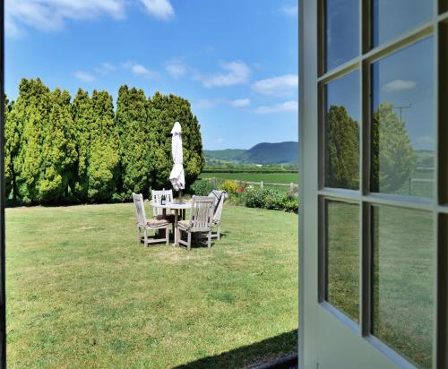 una mesa con sillas y una sombrilla en el césped en Country Cottage with Far Reaching Views, en Presteigne