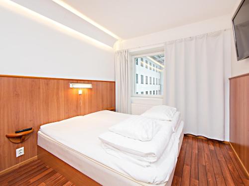 a small bedroom with a bed and a window at Omena Hotel Turku Humalistonkatu in Turku