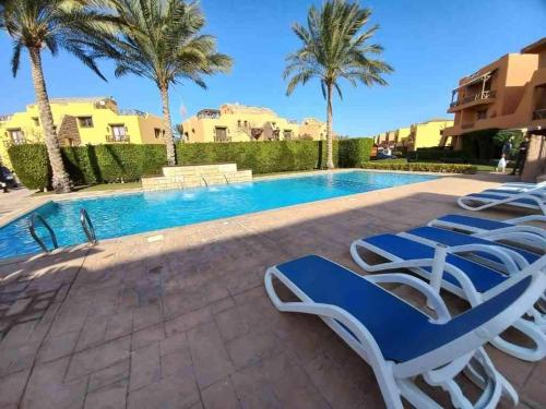 a swimming pool with lounge chairs and palm trees at Luxury Chalet in Mountain View 2 , El-Sokhna with Sea View , Pool View and Garden View Families Only in Ain Sokhna