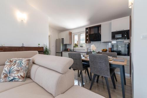 a living room with a couch and a table with chairs at Amazing sea view apartment- Romantica in Kastel Stafilic