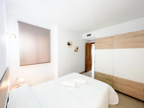 a bedroom with a white bed and a mirror at Apartment on the 1st line of the Sabinillas beach with sea views in San Luis de Sabinillas