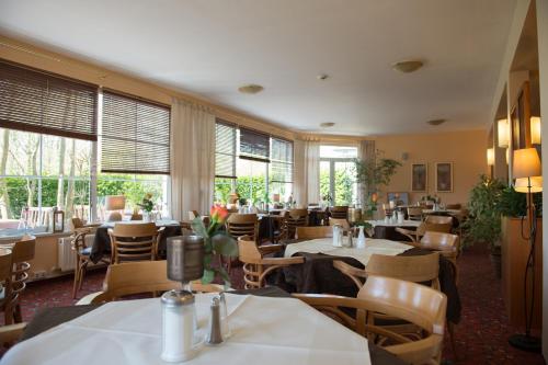 a restaurant with tables and chairs and windows at Montana Hotel Senden in Senden