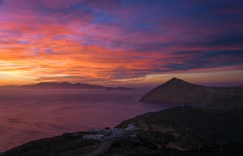 a sunset over a mountain with a town on it at Aegean Balcony Studio in Ano Meria