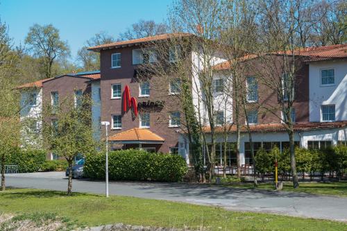 a large brick building with a flag in front of it at Montana Hotel Senden in Senden